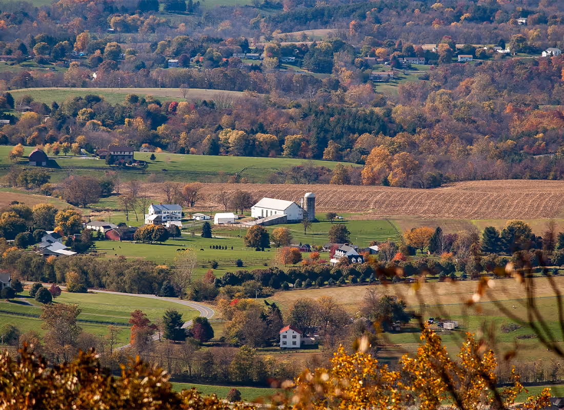 Aerial view of a rural farmland landscape with barns and fields in fall foliage