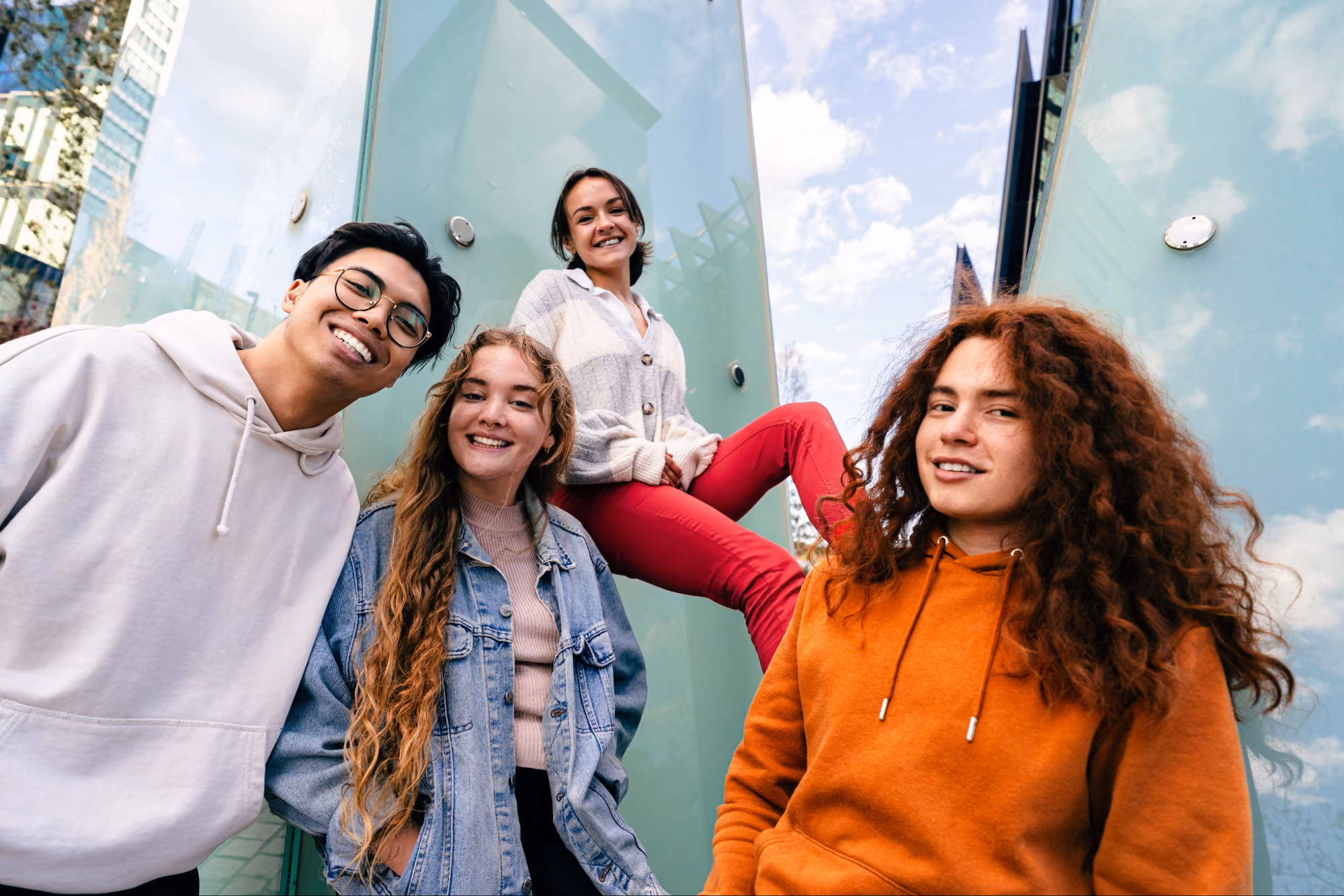 Group of young friends smiling together outdoors near a glass building
