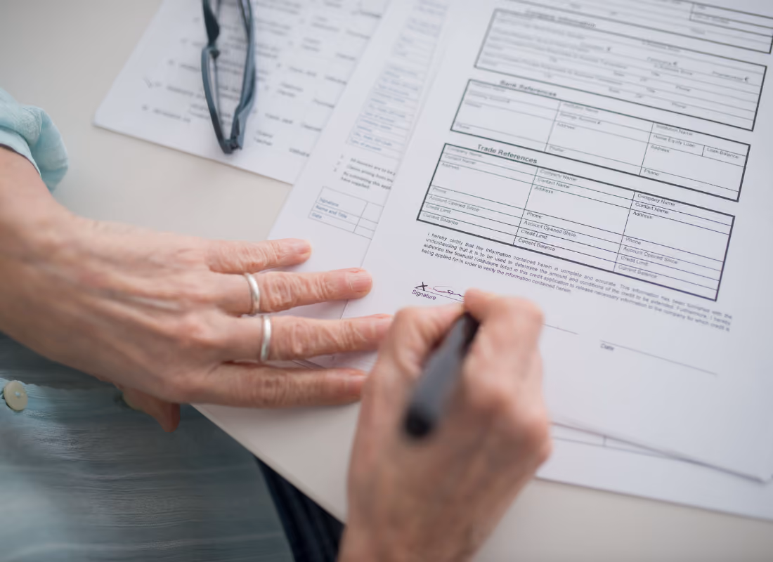 Close-up of a hand signing a paper form, representing state applications for a Section 1115 Medicaid waiver