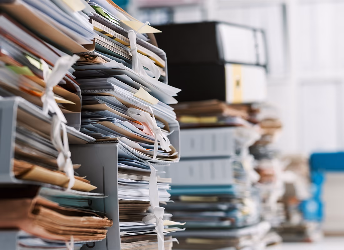 Rows of overstuffed file folders and paperwork stacked on office shelving