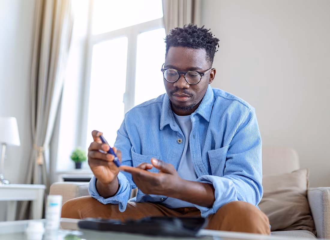 Man checking his blood glucose level with a fingerstick monitor at home