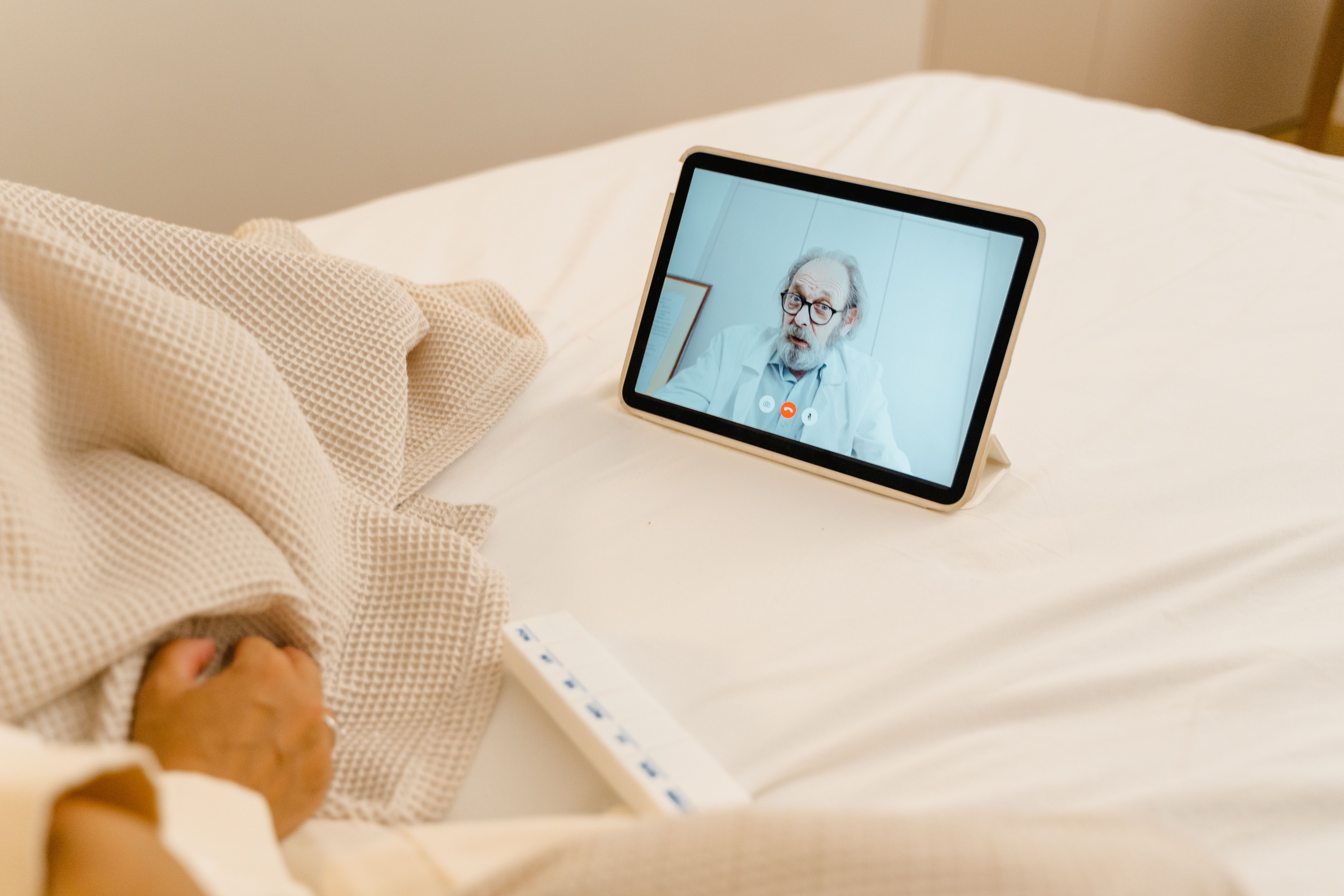 Patient in a hospital bed having a video call with a doctor on a tablet, representing a virtual health visit
