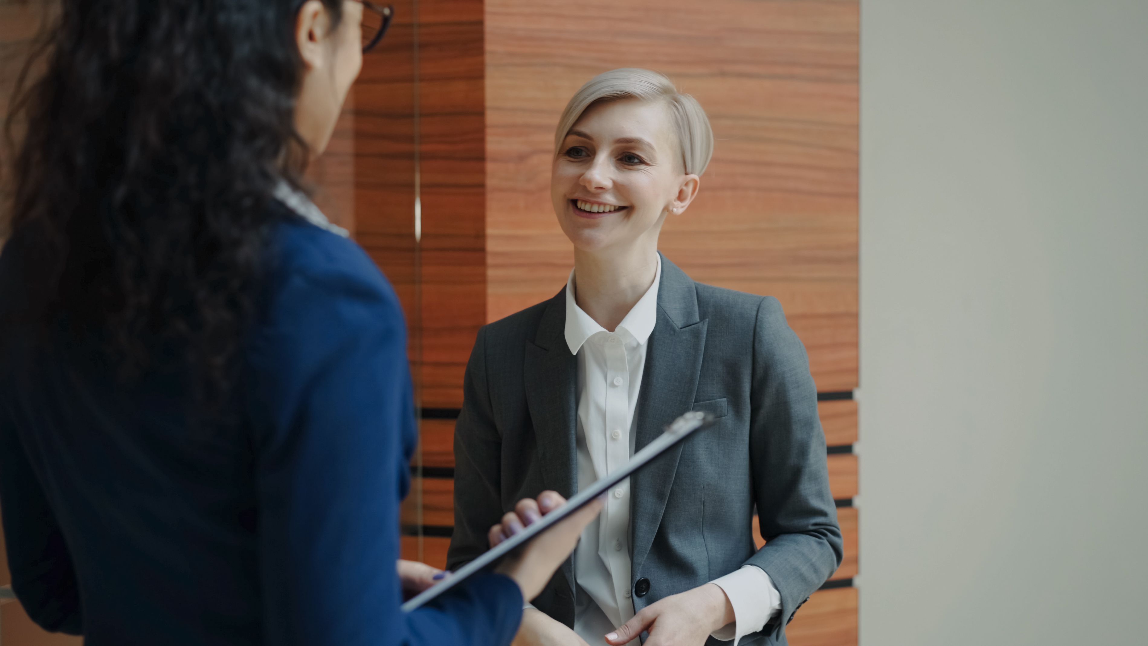 Two professionals in a business consultation, one holding a clipboard, representing a stop loss insurance discussion.