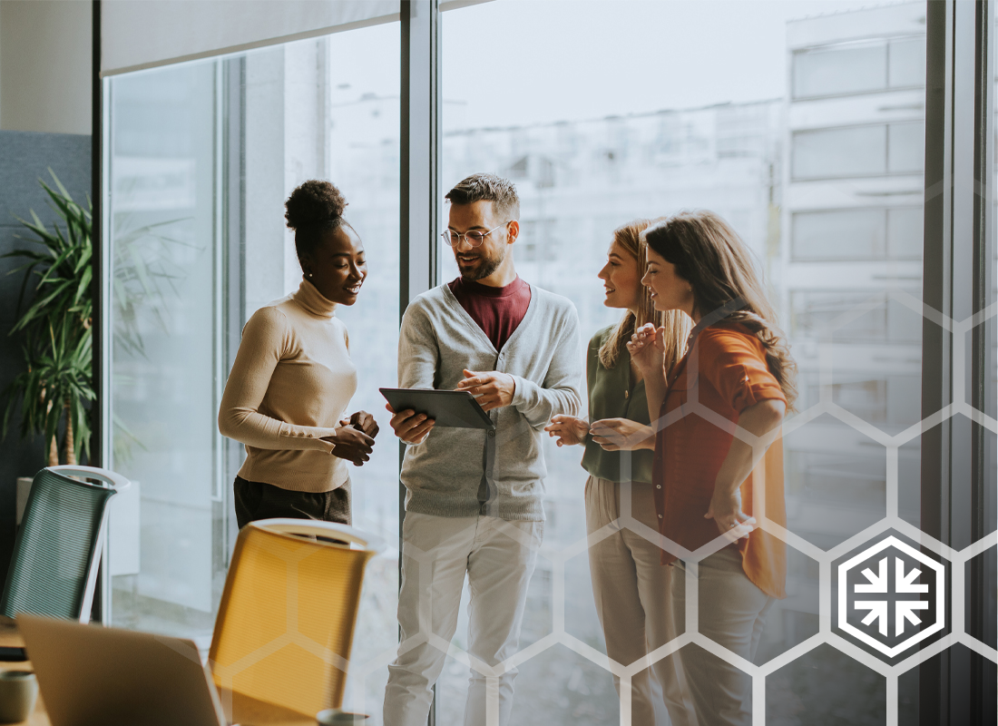 Coworkers discussing a tablet in a bright office by floor-to-ceiling windows, overlaid with the OnMed hexagon brand pattern.