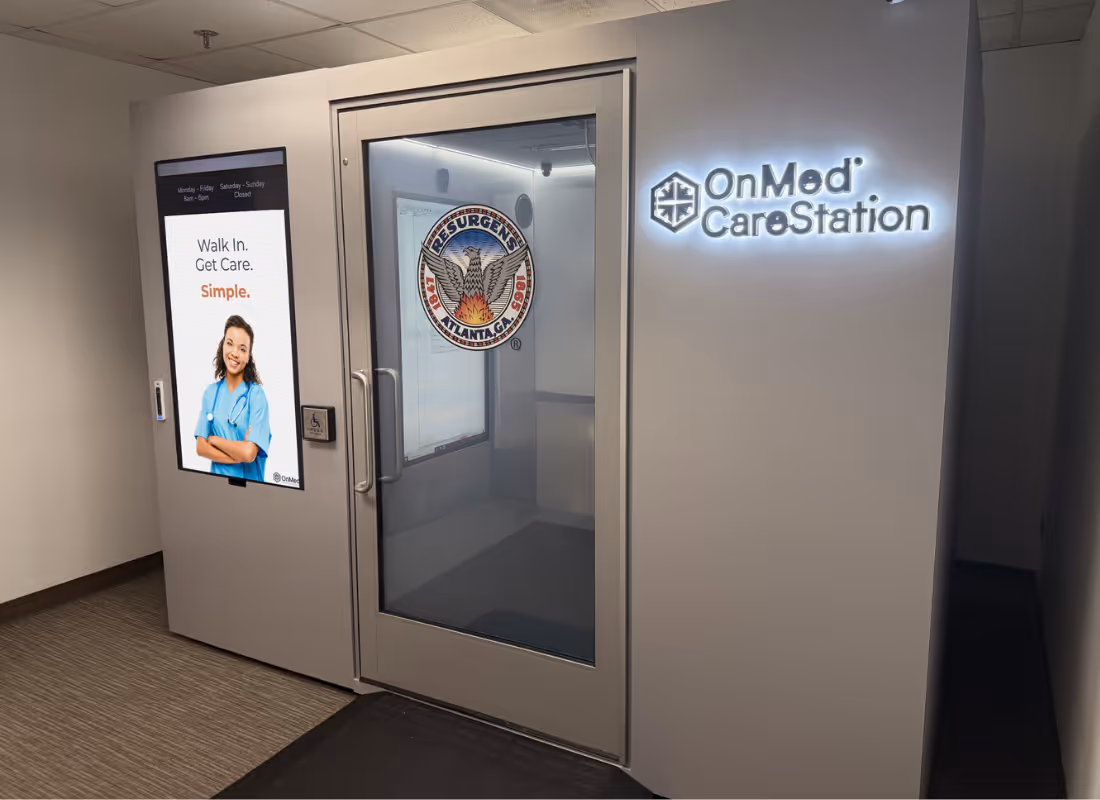 OnMed CareStation® health kiosk with backlit logo and Resurgens Atlanta seal on the door, installed in an office hallway