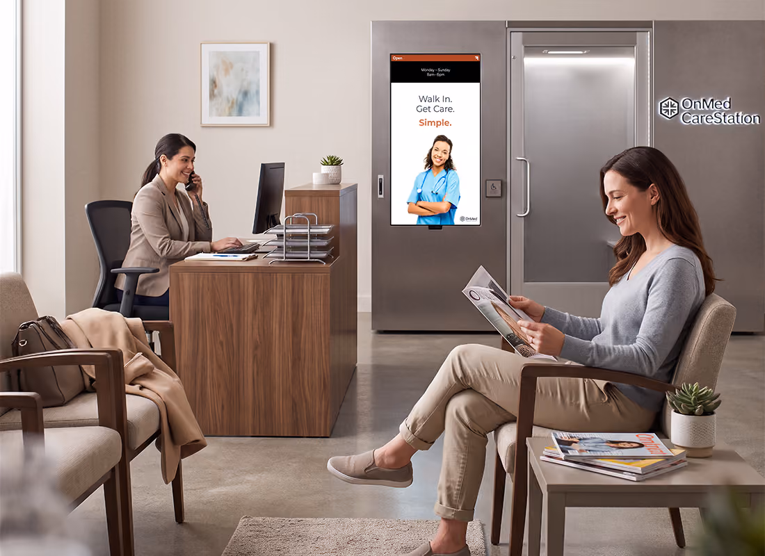 Woman reading a magazine in a clinic waiting room near the OnMed CareStation® displaying "Walk In. Get Care. Simple." as a receptionist works at the desk