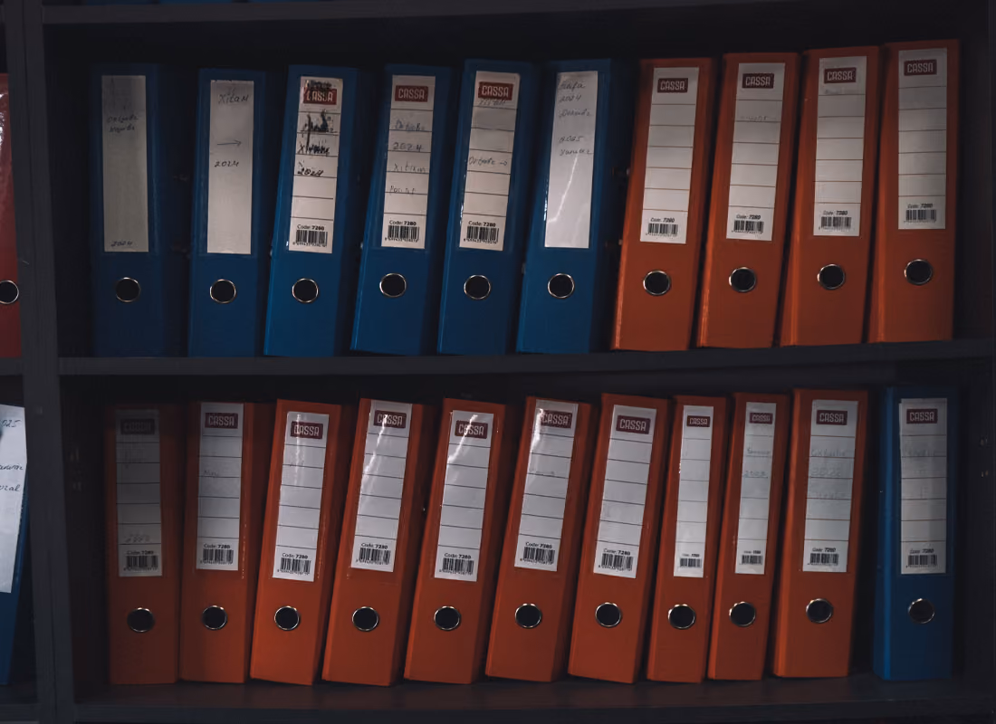 Rows of blue and orange binders with labeled spines stacked on dark shelves