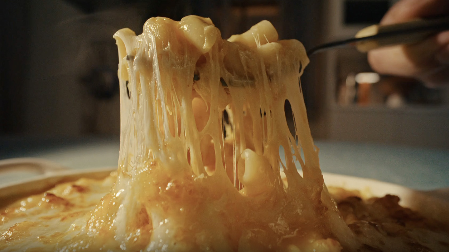Fromage fondu étiré avec une fourchette sur un plat chaud.