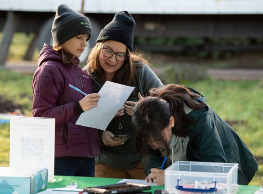 three people group at a table signing up on forms