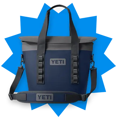 Navy blue YETI cooler bag with black handles and shoulder strap on a blue starburst background.