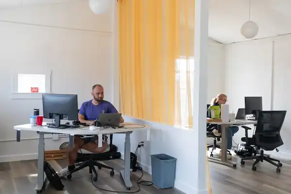 Two SignpostAI employees working at separate desks in a bright modern office.