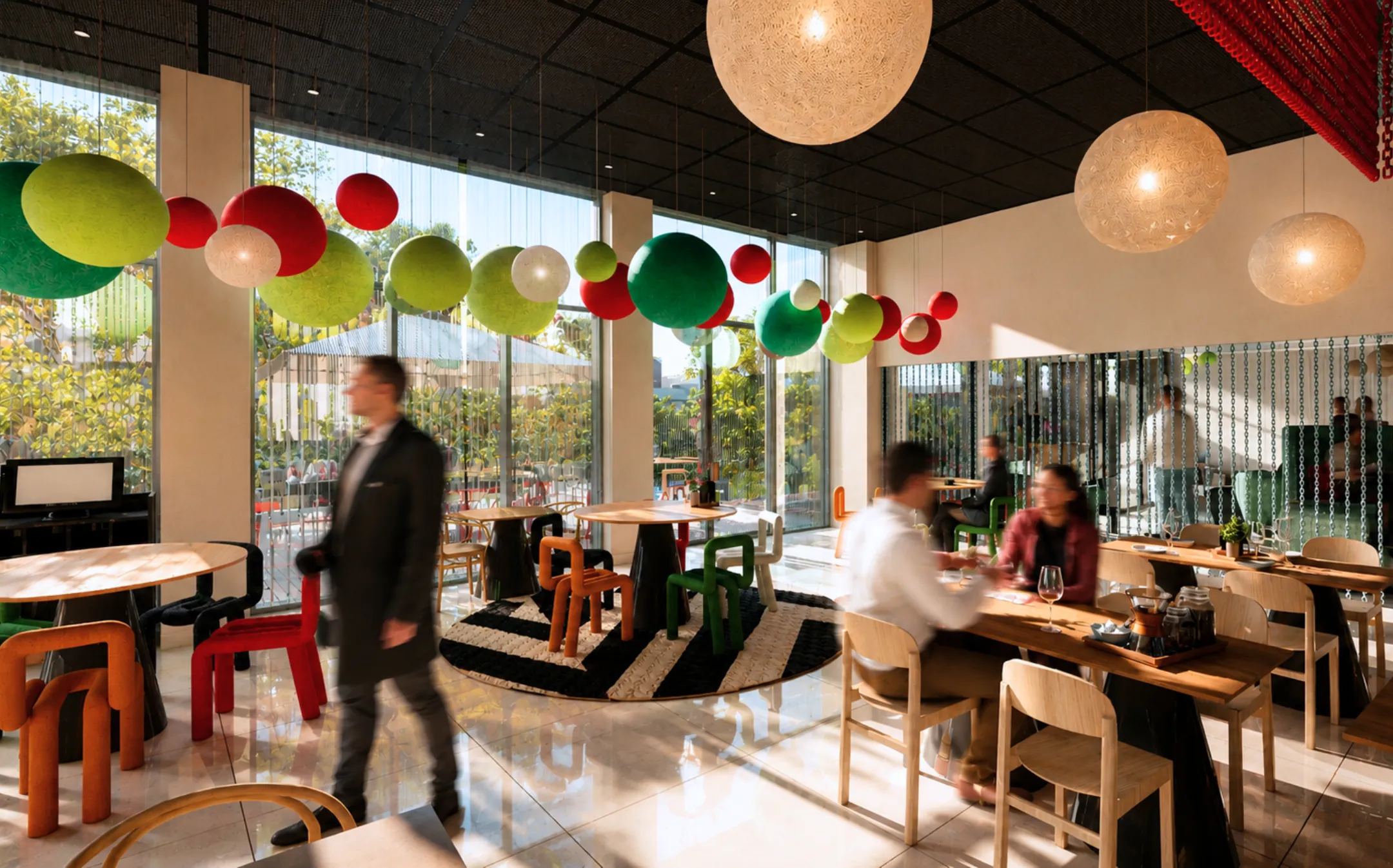 Intérieur moderne de café avec décorations sphériques colorées suspendues et personnes floues en mouvement.