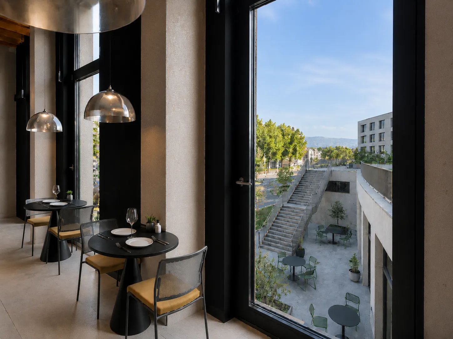 Vue depuis l'intérieur de l'hôtel Ysotop sur la terrasse extérieure et le rez-de-jardin de la Presqu'île scientifique de Grenoble.