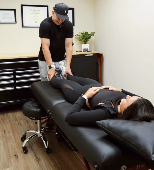 Therapist stretching a woman's legs on a padded treatment table in a wellness clinic.