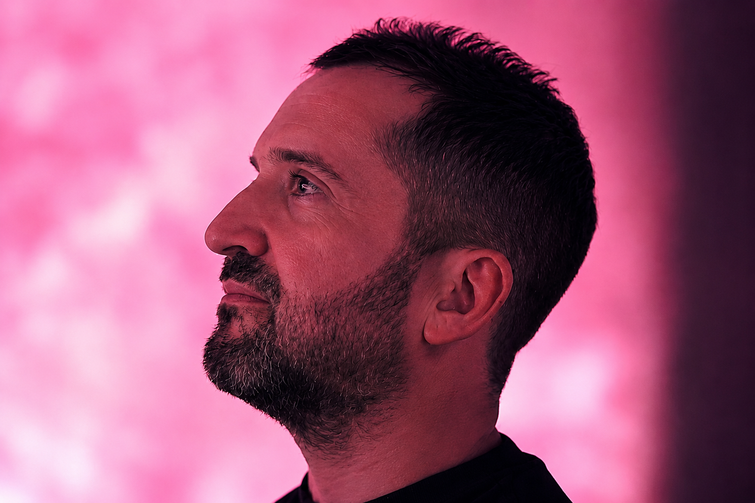 Michael Couzigou in profile against magenta bokeh background