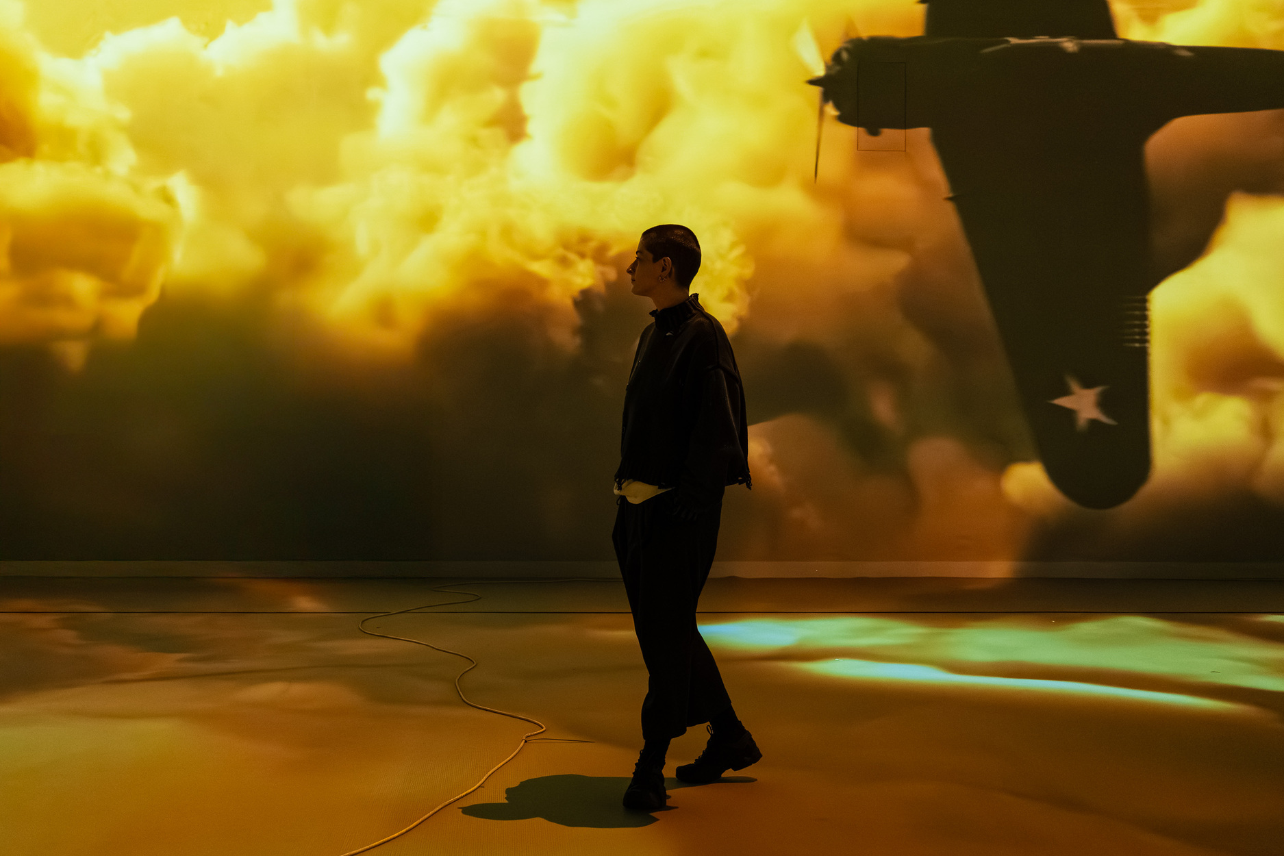 Person walks through golden immersive projection with aircraft silhouette