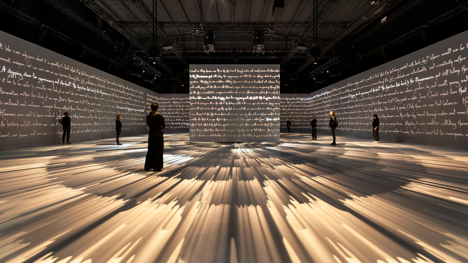 Silhouetted visitors in room with white handwriting wall projections
