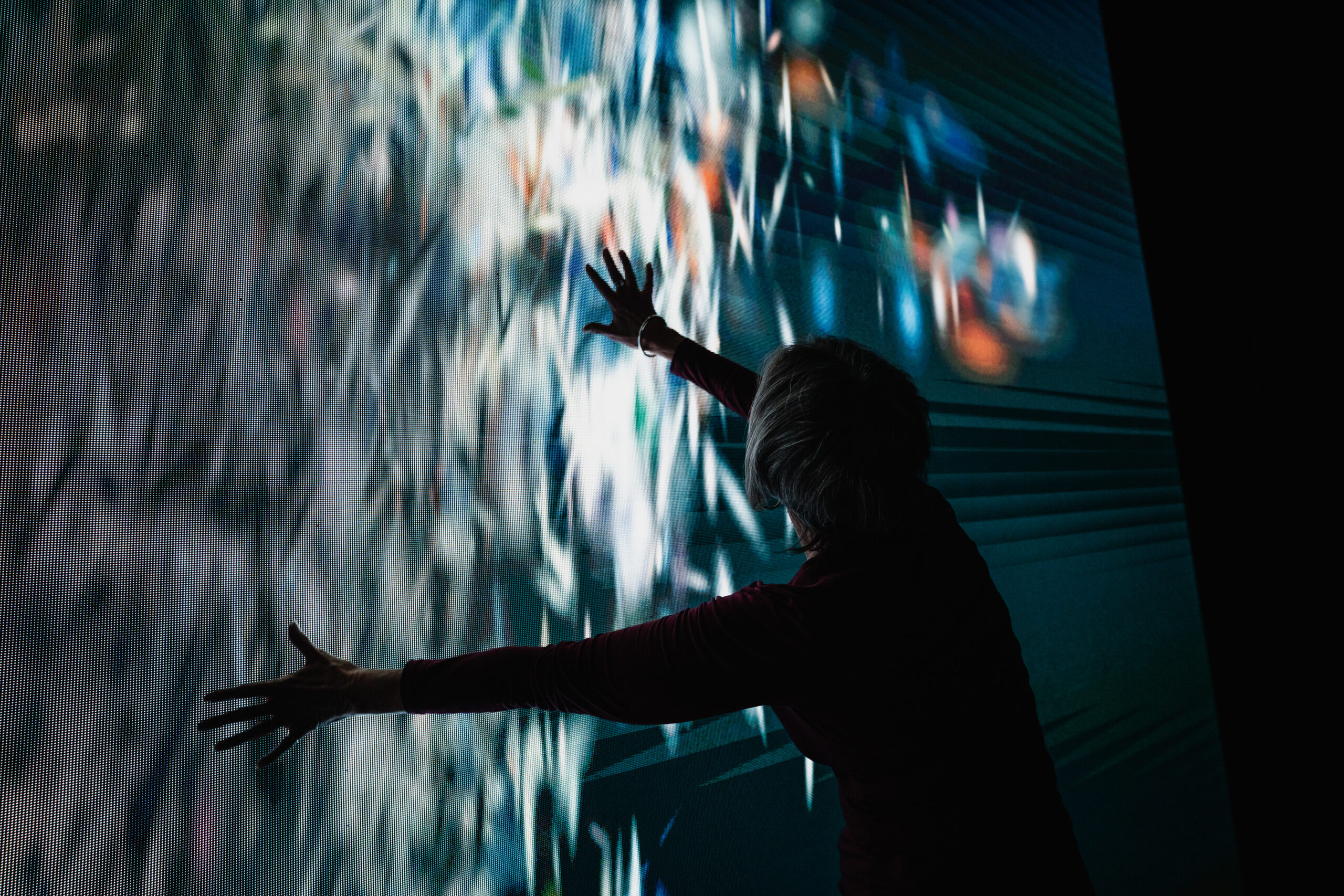 Colorful light streaks ripple across a curved immersive display