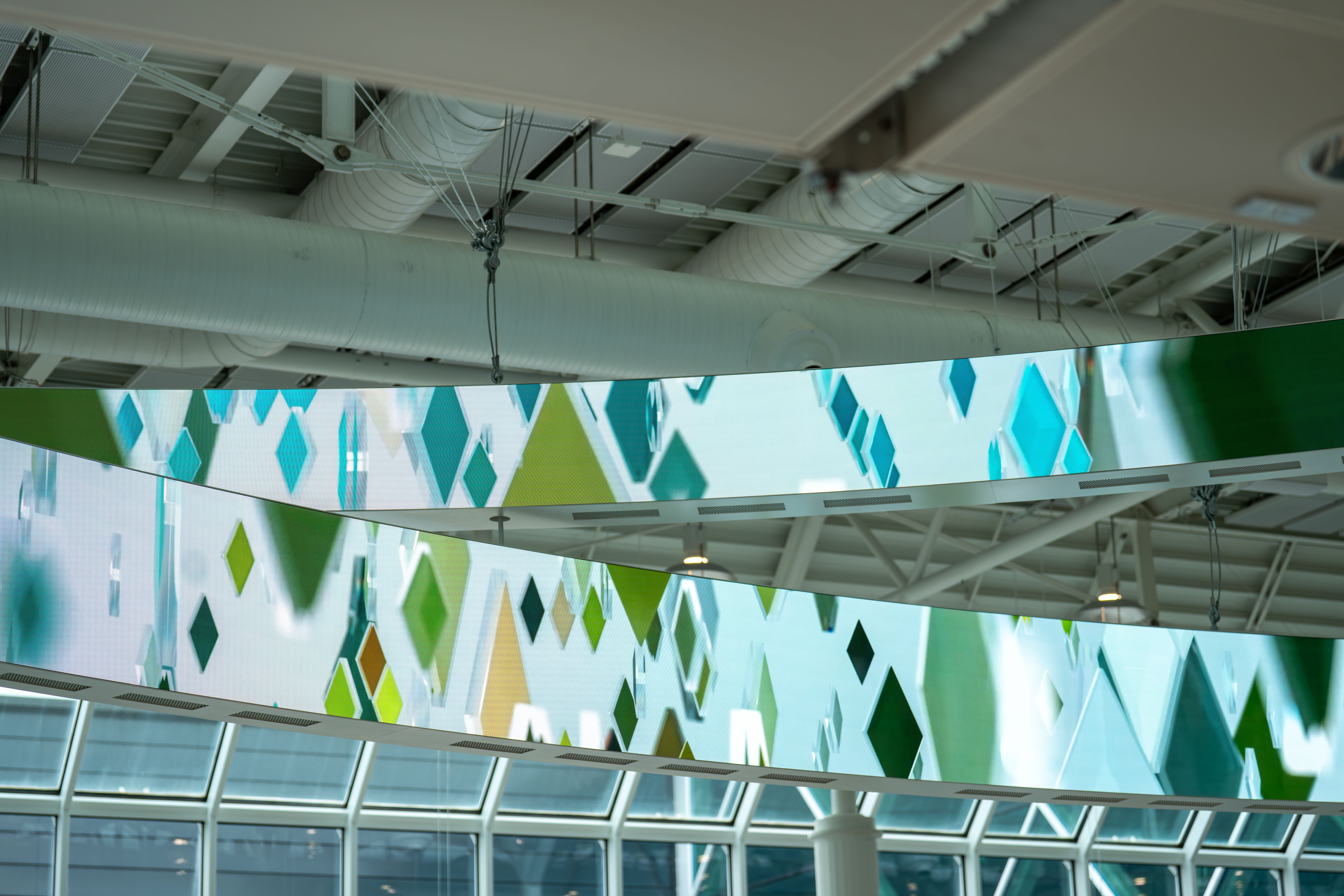 Curved LED ribbons with green diamond patterns in airport hall
