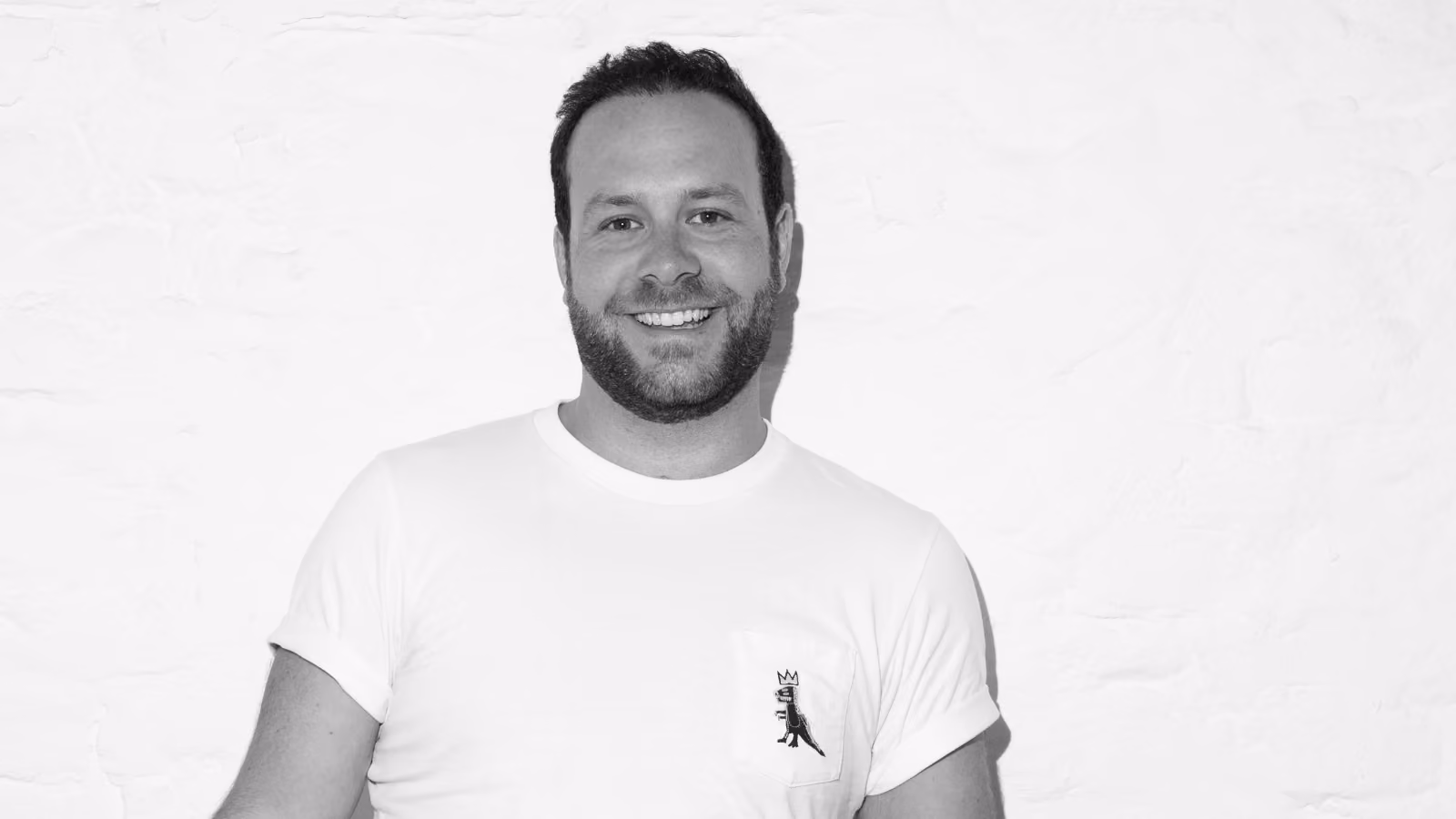 Black and white portrait of smiling Luc Moser against textured wall