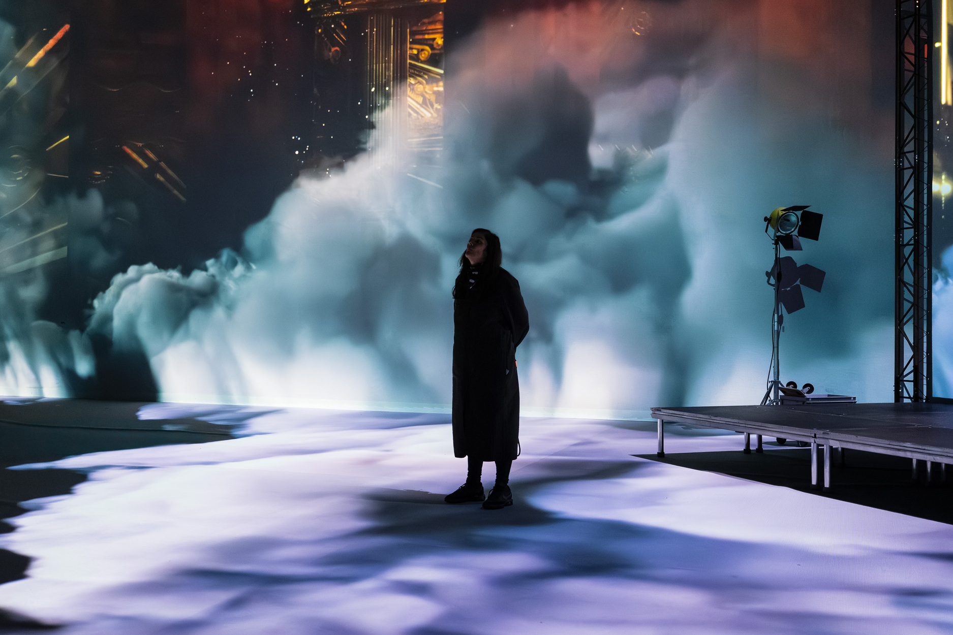 Person silhouetted against towering cloud projection installation