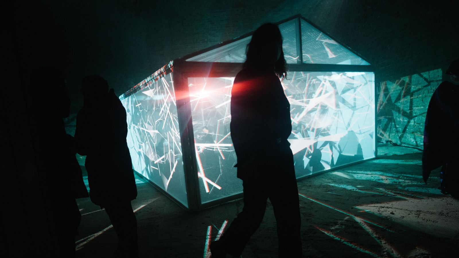 Teal-lit cube projects sharp white geometric lines onto the floor