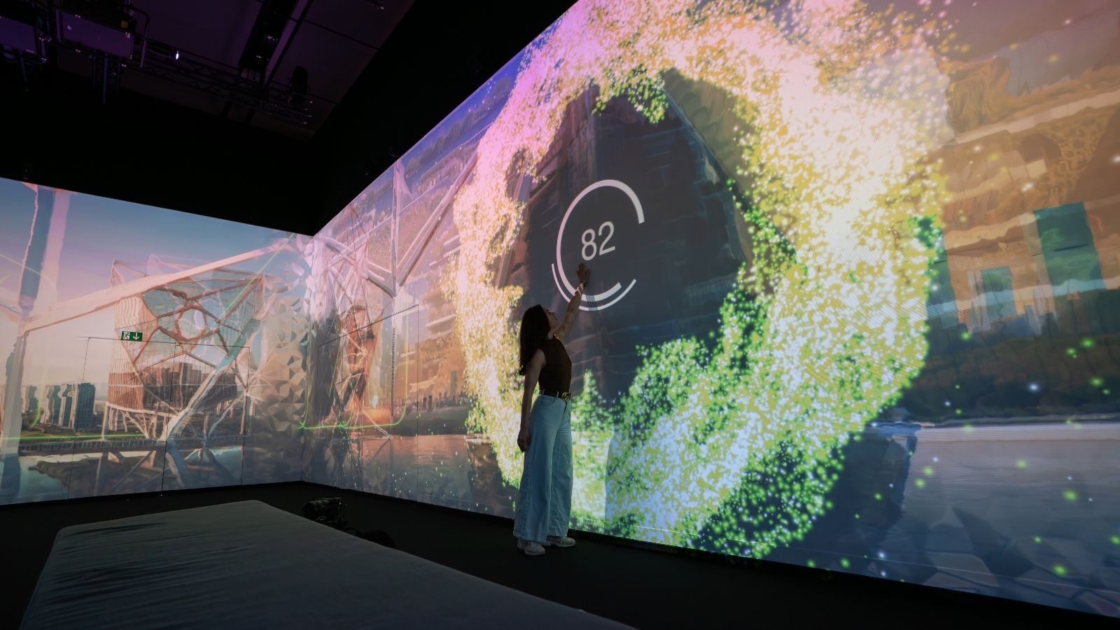 Person touches a glowing circular display on a large immersive screen