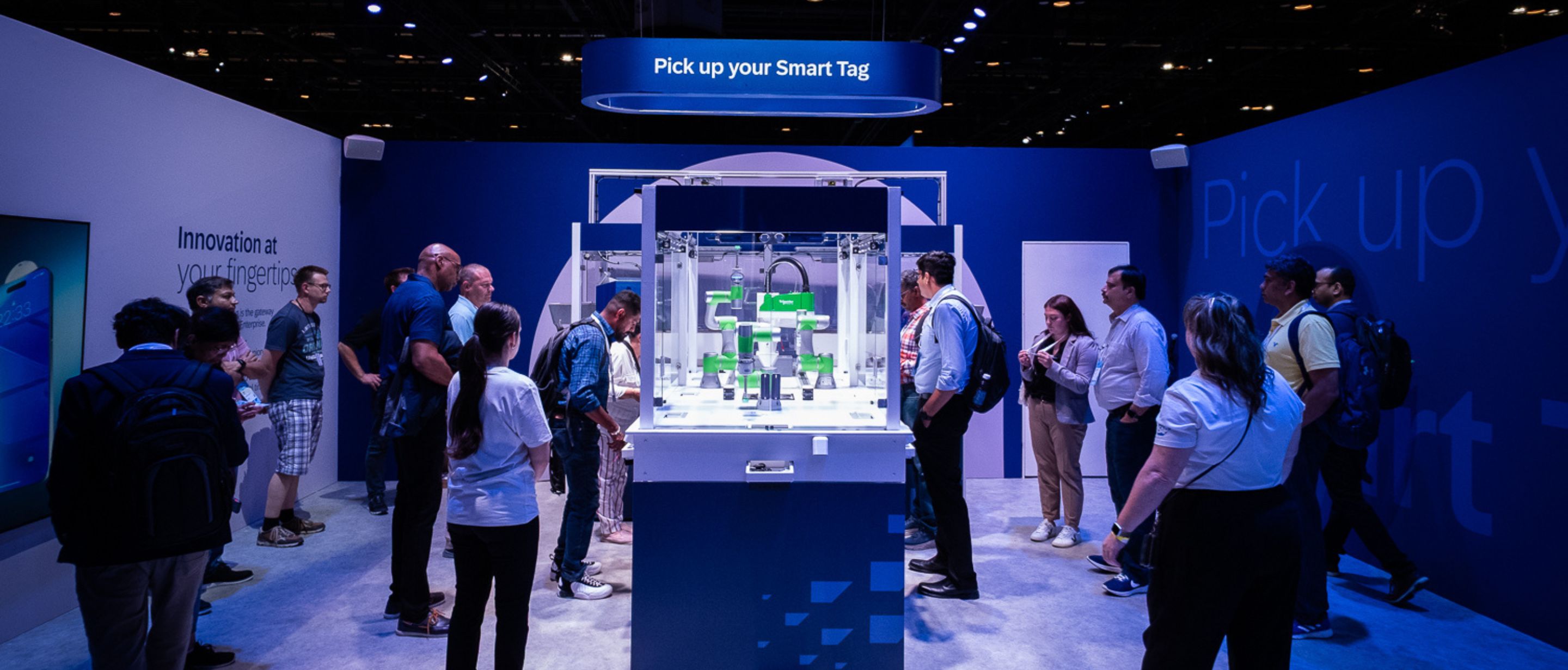 Trade fair crowd gathers around robotic arms beneath a Smart Tag sign