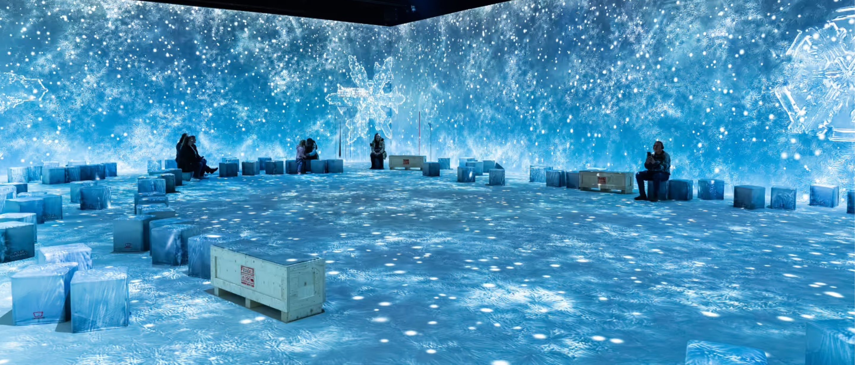 Blue water ripples cover the floor around glowing ice-cube seating