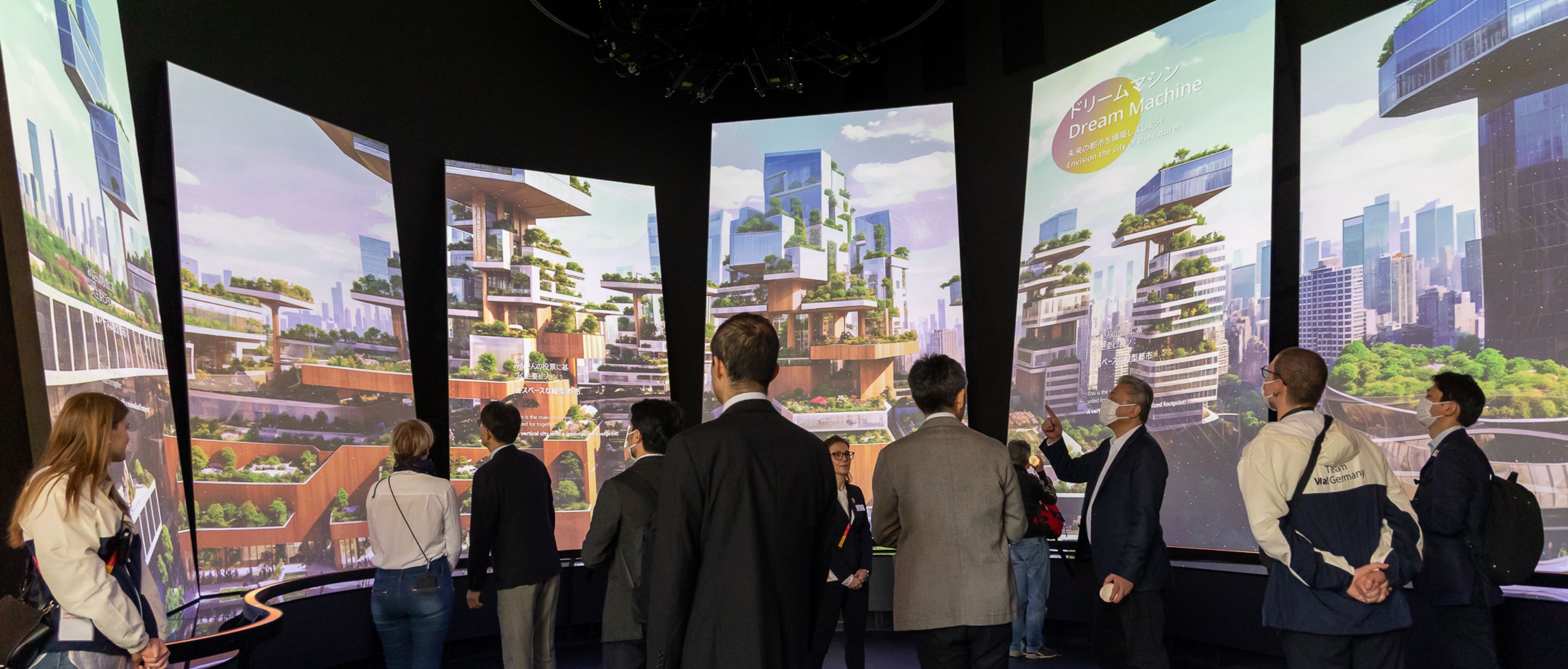 Visitors view curved screens showing a green terraced future city