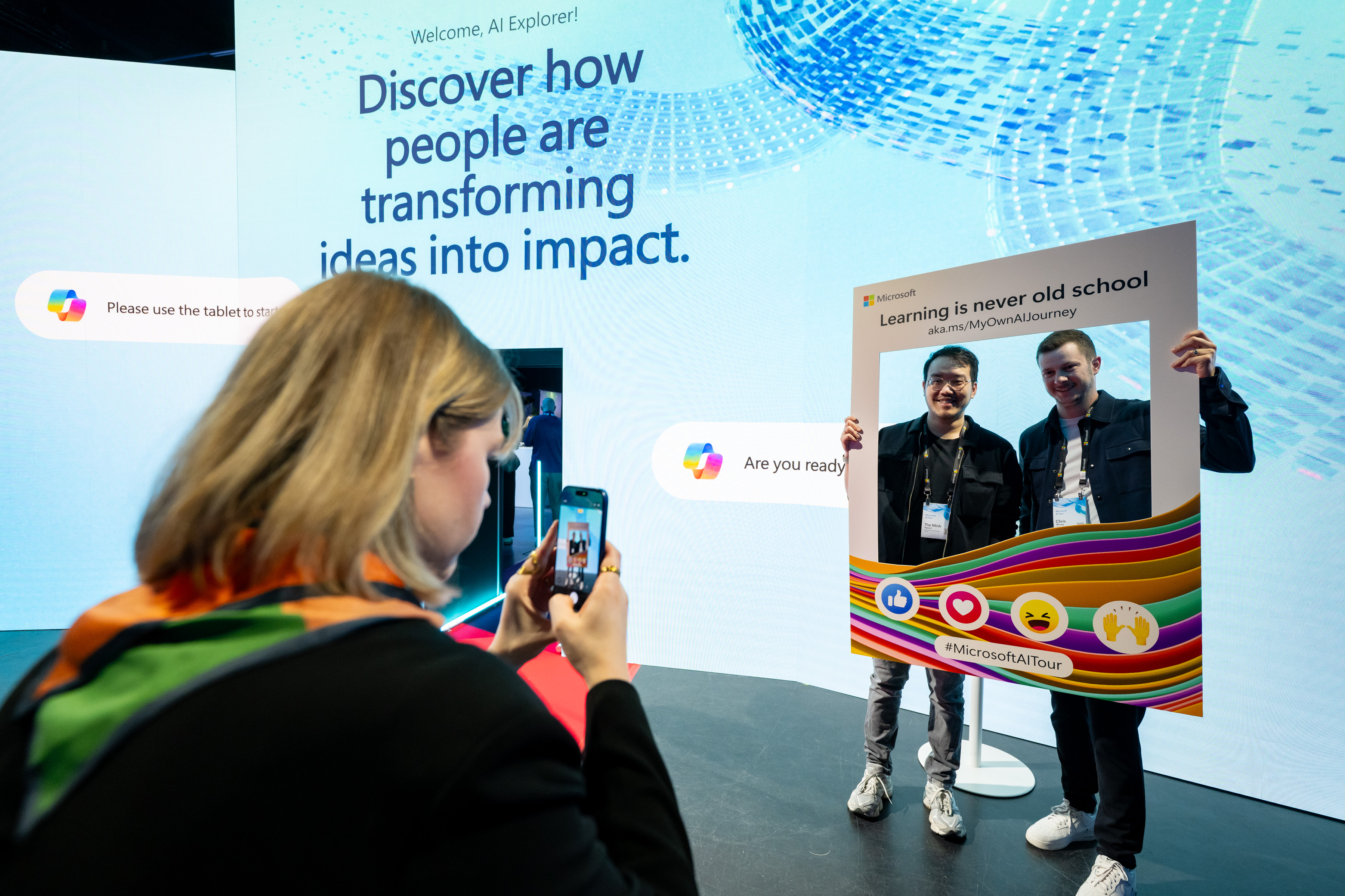 Attendees pose with a Microsoft AI Tour social media frame prop