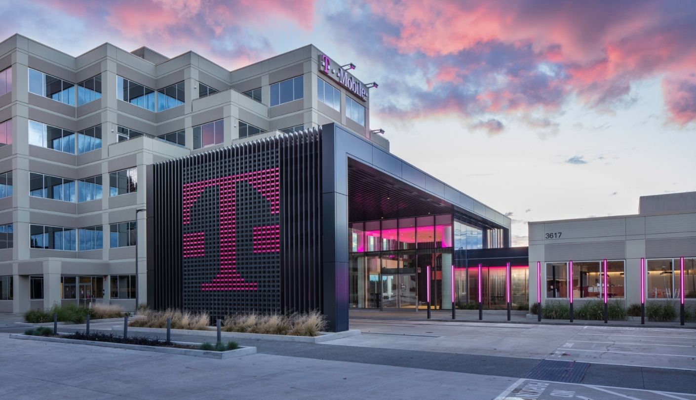 T-Mobile headquarters entrance glows pink at dusk beside a logo wall