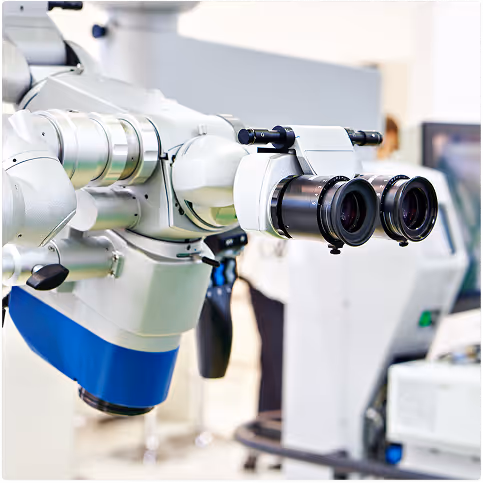 Close-up of a modern surgical microscope with dual eyepieces in a medical setting.