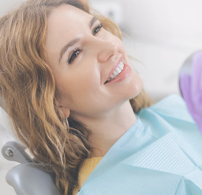 Woman smiling while sitting in a dental chair wearing a dental bib.