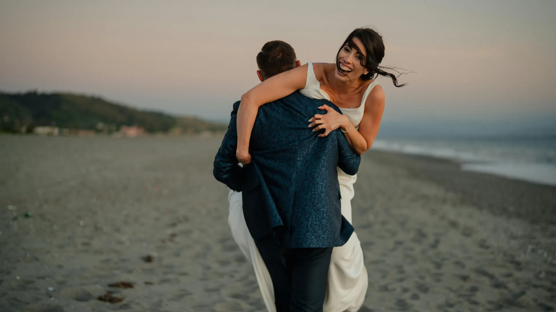 A bride and groom laughing on the beach