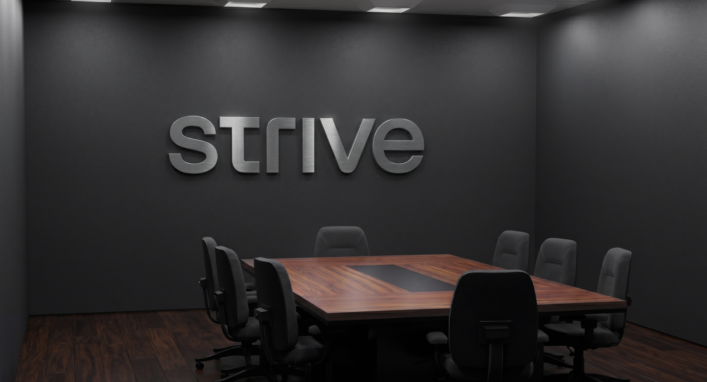 Modern conference room with a wooden table, eight black office chairs, and the word 'strive' displayed in metallic letters on a dark gray wall.