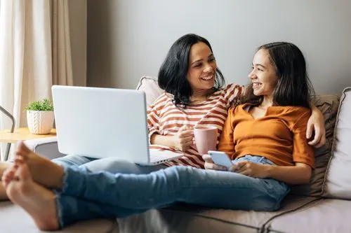 Mother and Daughter on couch with electronics stock image