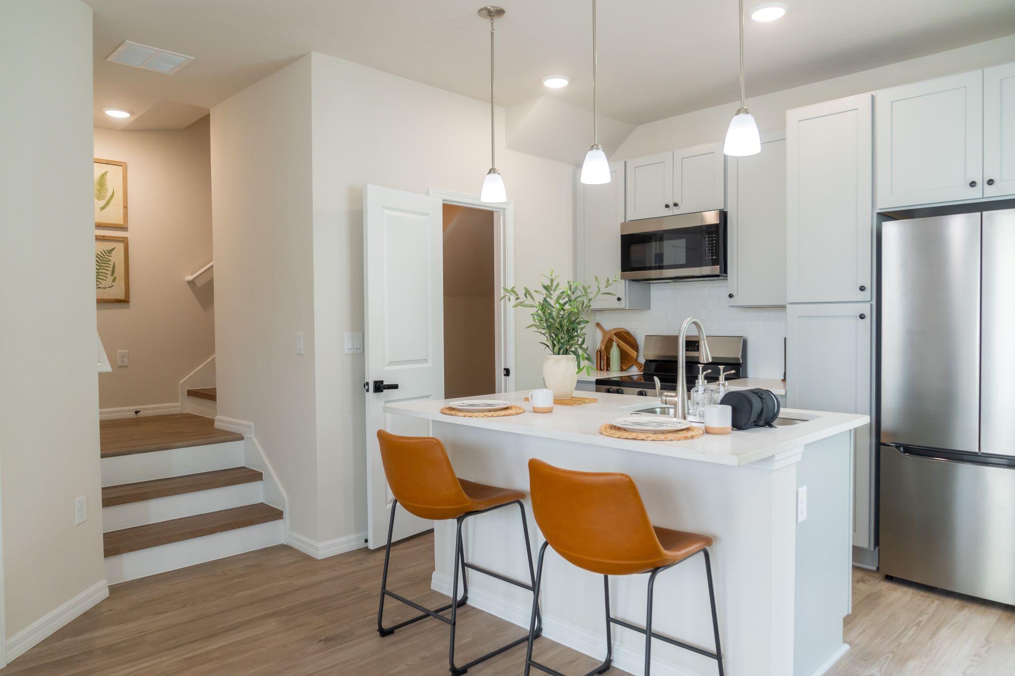 3D Rendering of Kitchen with island, white cabinets, stainless steel appliances and stairs
