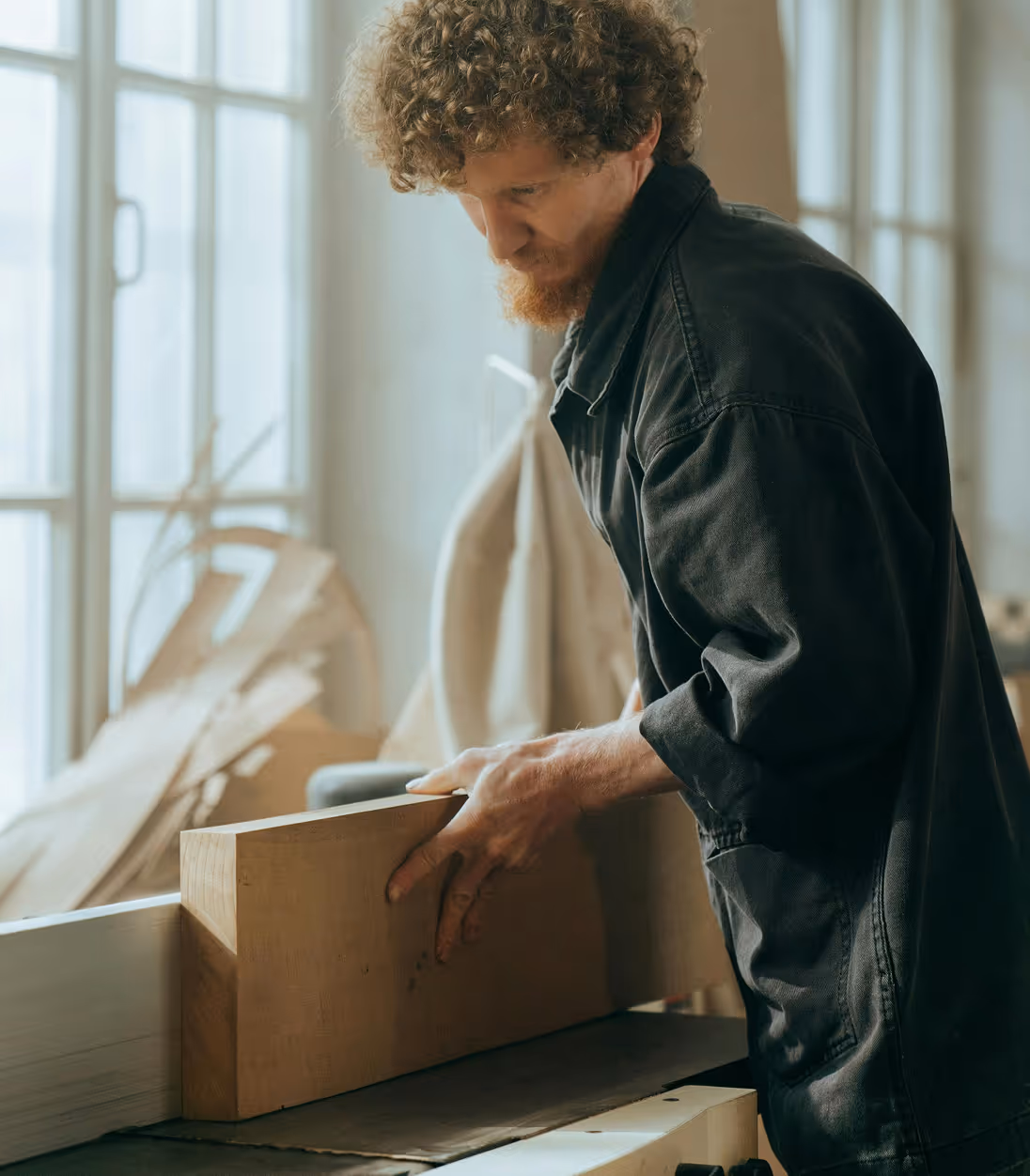 Homme travaillant le bois avec une machine dans un atelier lumineux.