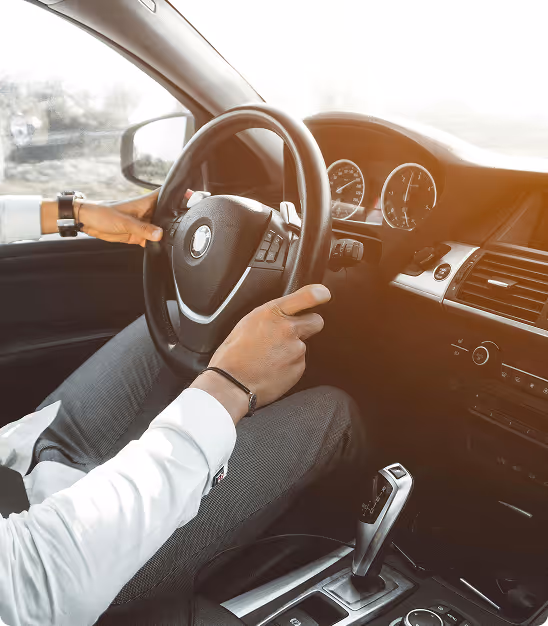 Personne tenant le volant d'une voiture moderne avec tableau de bord et levier de vitesse automatique.