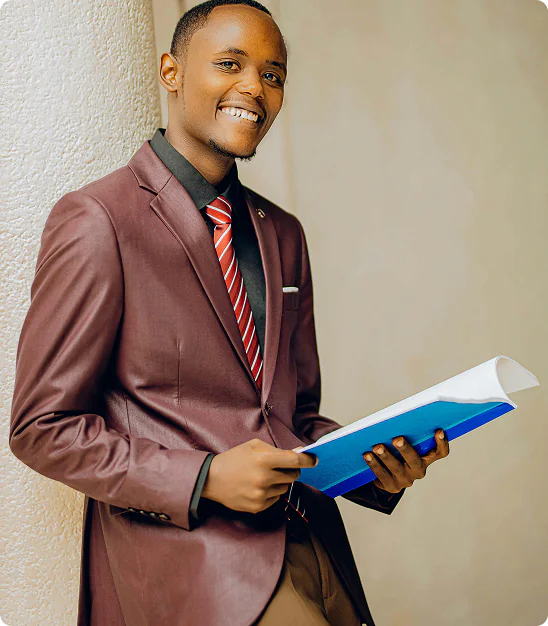 Jeune homme souriant en costume marron et cravate rouge tenant un dossier bleu.