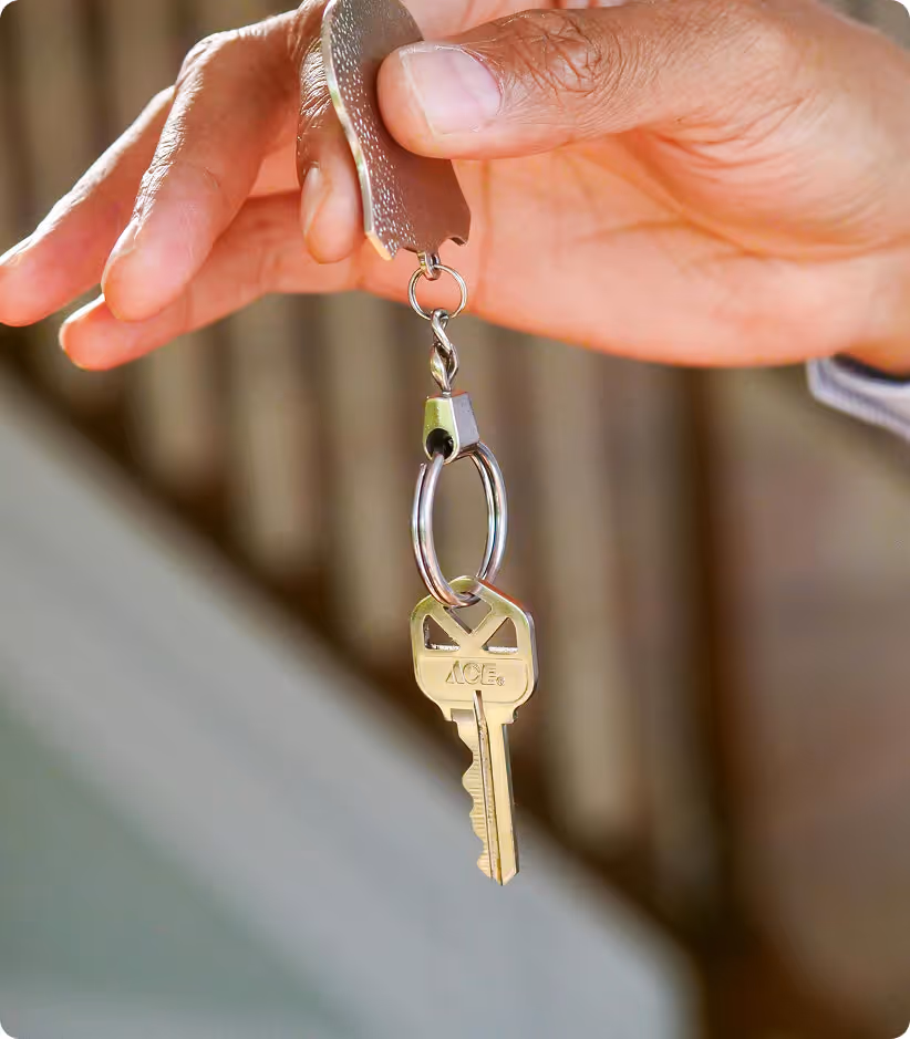 Main tenant un porte-clés avec une clé en métal argenté suspendue.