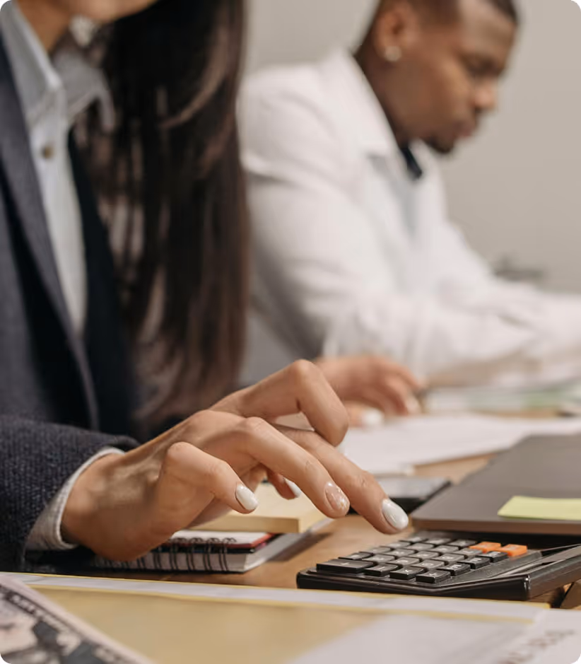 Deux professionnels utilisent une calculatrice et un ordinateur portable au bureau.