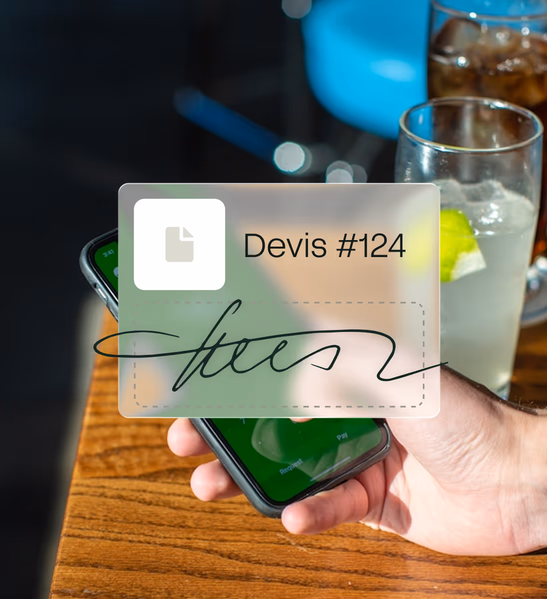 Main tenant un smartphone montrant une signature numérique sur un devis #124 avec deux verres en arrière-plan.