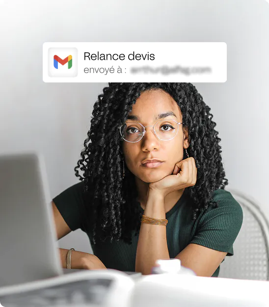 Jeune femme aux cheveux bouclés et lunettes regarde l'ordinateur avec un message Gmail 'Relance devis'.
