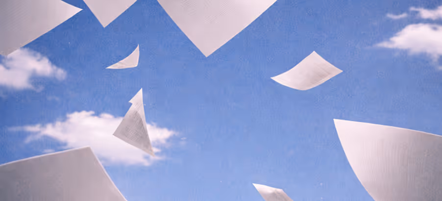Des feuilles de papier blanches flottant dans un ciel bleu avec quelques nuages blancs.
