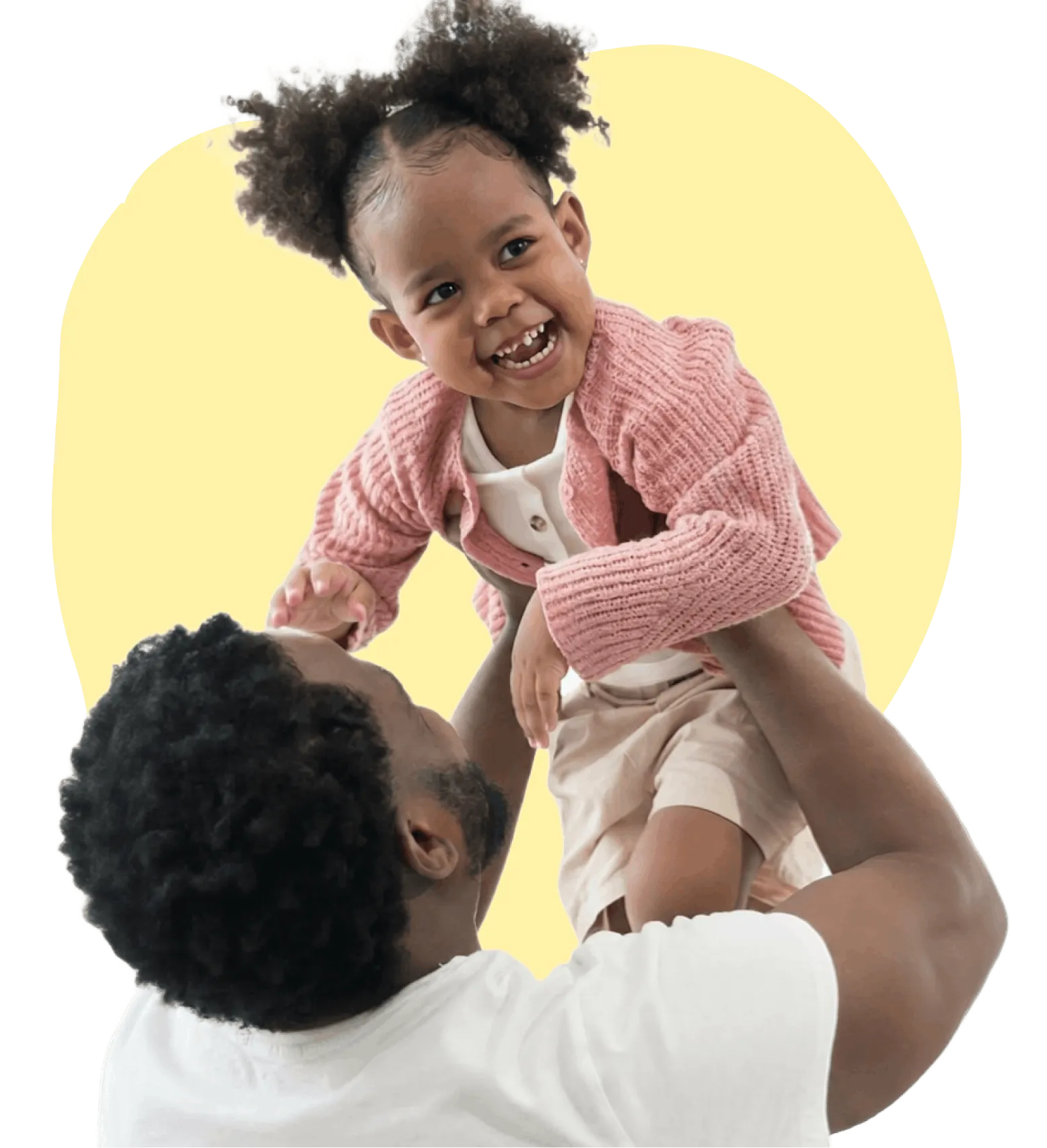 Smiling father lifting his young daughter wearing a pink sweater against a yellow background.