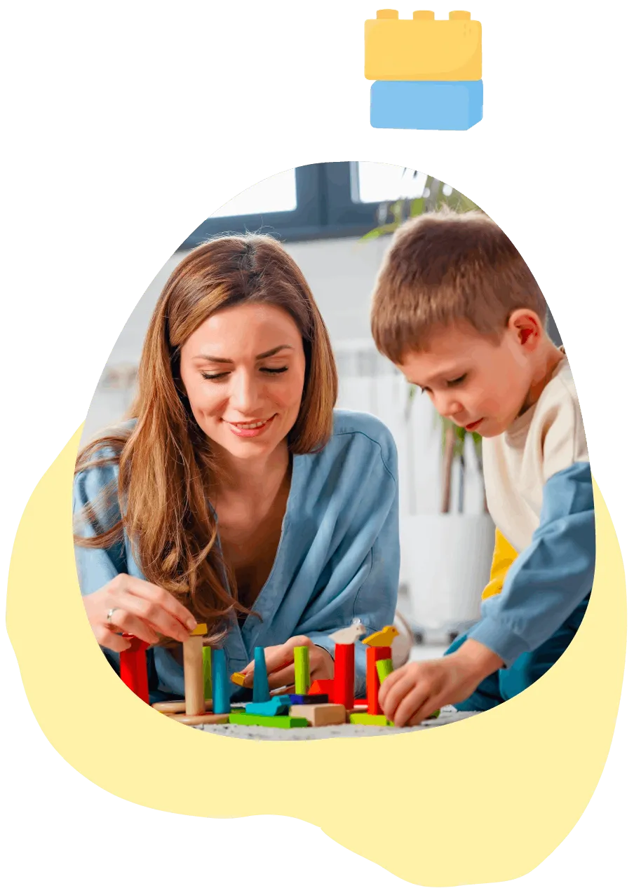 Woman and child playing with colorful wooden blocks on the floor near a window.