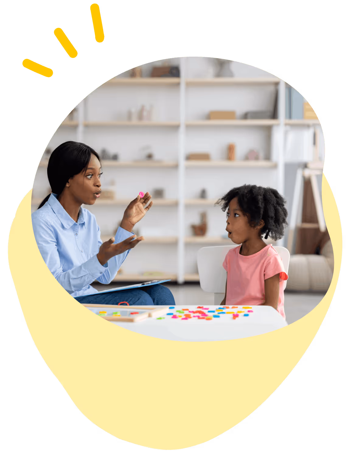 Woman in blue shirt holding object, teaching young girl in pink shirt at a table with colorful letters.