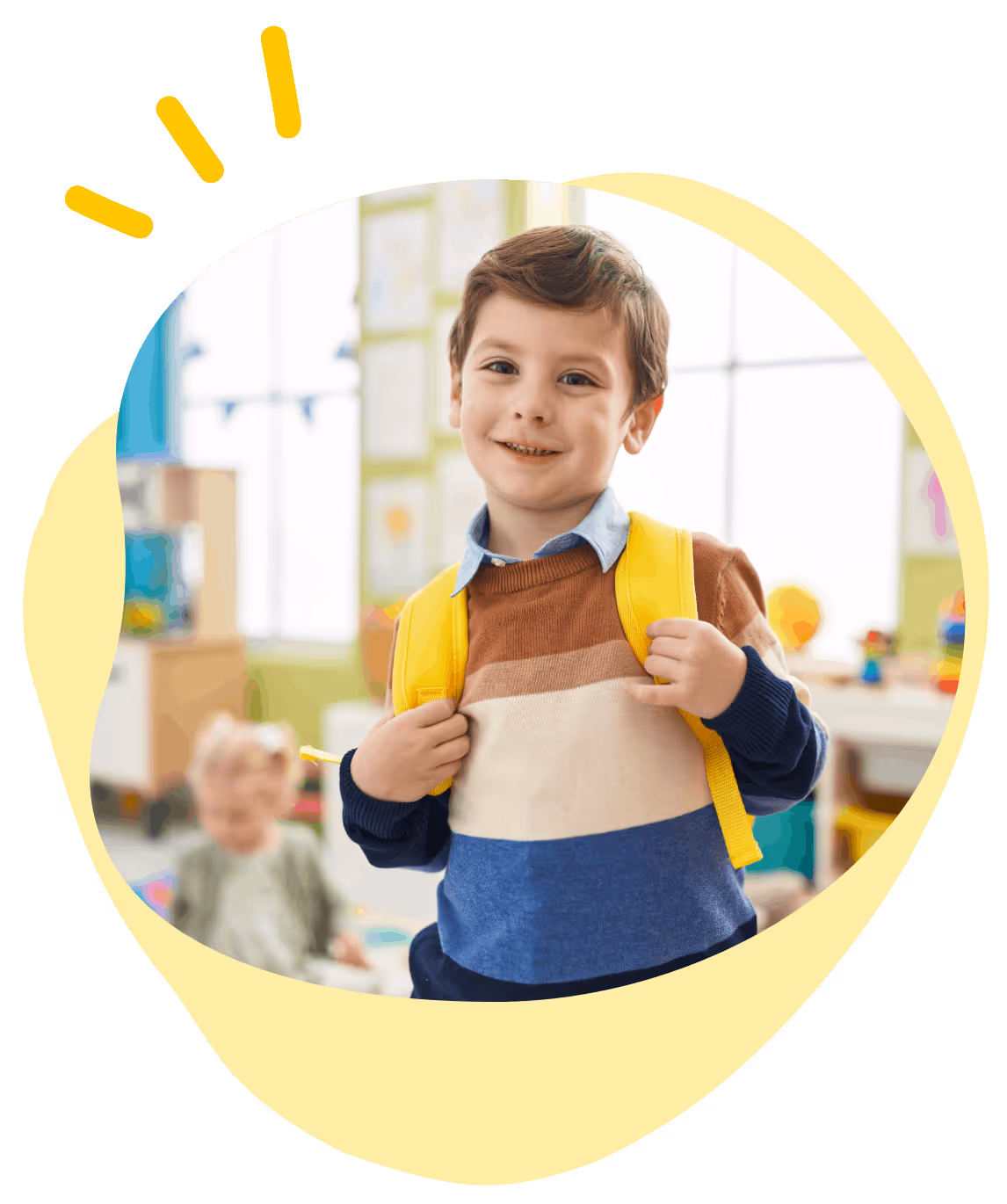 Smiling young boy with a yellow backpack in a colorful classroom setting.